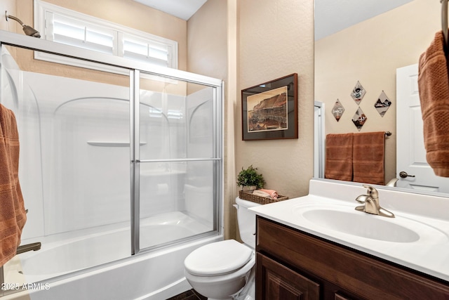 full bathroom featuring vanity, combined bath / shower with glass door, and toilet