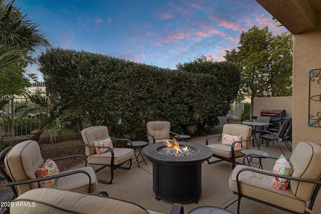 patio terrace at dusk featuring grilling area and a fire pit