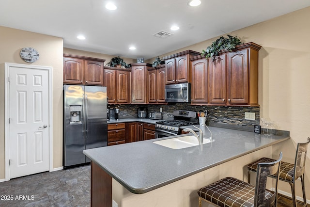 kitchen featuring sink, appliances with stainless steel finishes, a kitchen breakfast bar, kitchen peninsula, and backsplash