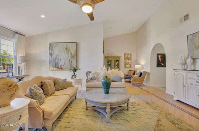 living room featuring light hardwood / wood-style floors, vaulted ceiling, and ceiling fan