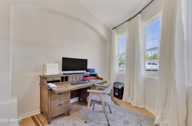 office space featuring vaulted ceiling, light wood-type flooring, and a wealth of natural light