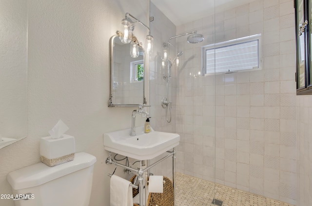 bathroom featuring toilet, sink, and tiled shower