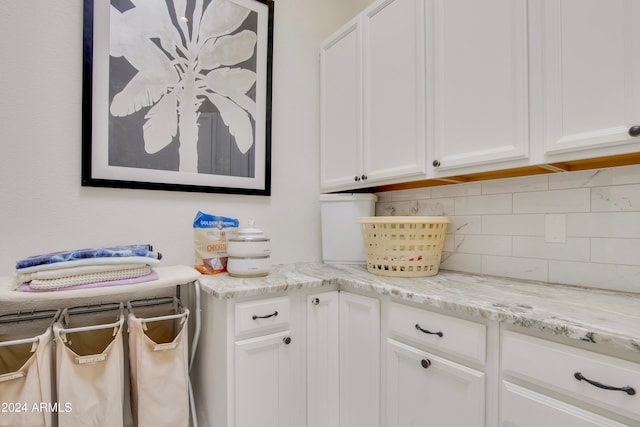 kitchen with white cabinetry, light stone countertops, and decorative backsplash