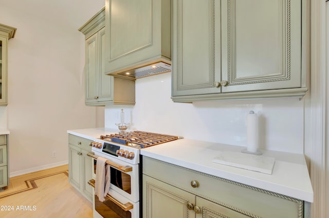 kitchen featuring custom exhaust hood, light wood-type flooring, and high end stove