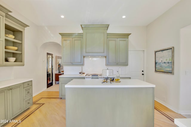 kitchen with stainless steel range oven, built in features, light hardwood / wood-style flooring, and a center island with sink