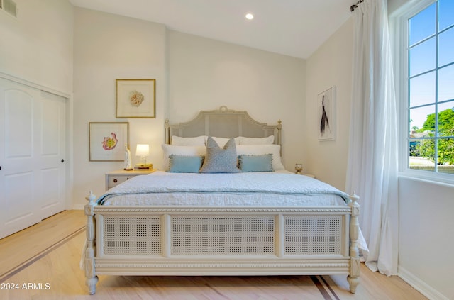 bedroom featuring light hardwood / wood-style flooring, multiple windows, and vaulted ceiling