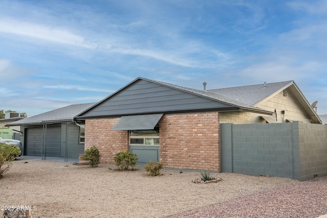 view of front of home with a garage, brick siding, fence, and roof with shingles