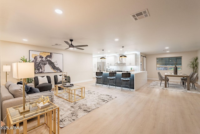 living area featuring ceiling fan, recessed lighting, visible vents, and light wood-style floors