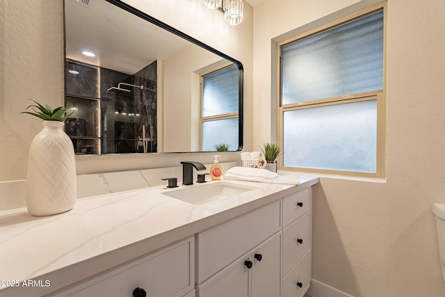 bathroom with a wealth of natural light, vanity, toilet, and walk in shower