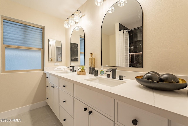 bathroom with tile patterned floors, a sink, baseboards, and double vanity