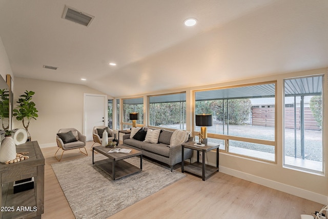 living room with lofted ceiling, plenty of natural light, light wood-style flooring, and visible vents