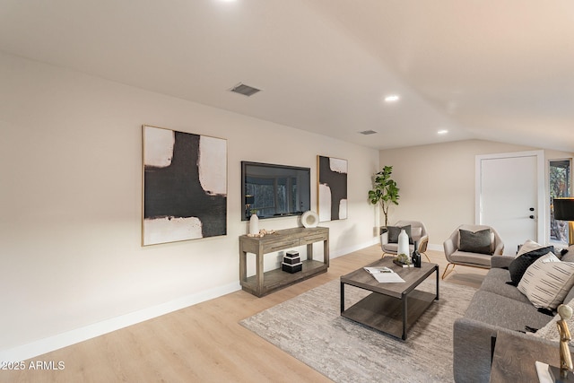 living area featuring visible vents, vaulted ceiling, baseboards, and wood finished floors