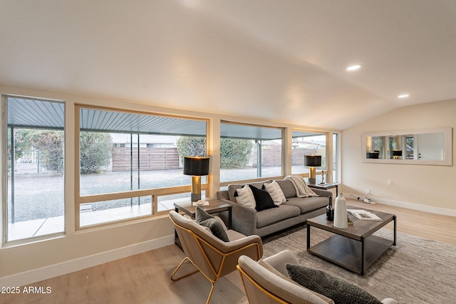 living room with a wealth of natural light, lofted ceiling, and light wood-style flooring