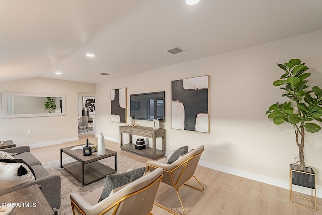 living room featuring vaulted ceiling, wood finished floors, visible vents, and baseboards