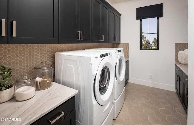 laundry room featuring light tile flooring, cabinets, and washer and clothes dryer