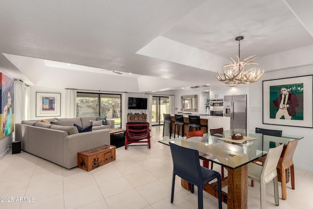 dining area with a textured ceiling, a tray ceiling, light tile patterned flooring, and a notable chandelier