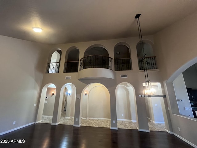 514 E Pearce Rd, Phoenix, AZ 85042 - unfurnished living room with arched walkways, wood finished floors, a towering ceiling, and baseboards