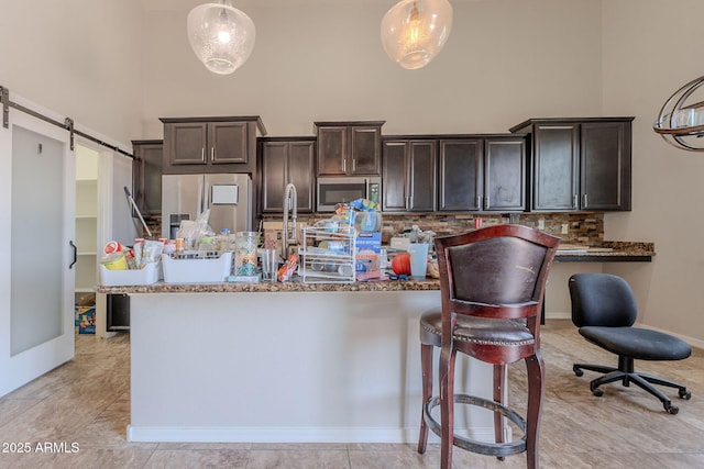 514 E Pearce Rd, Phoenix, AZ 85042 - kitchen featuring appliances with stainless steel finishes, a high ceiling, dark brown cabinetry, decorative backsplash, and stone countertops