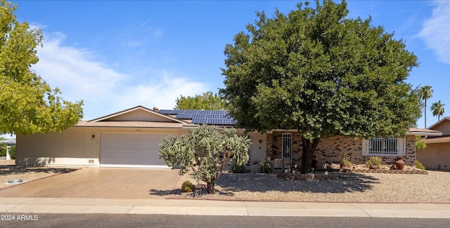 view of front facade featuring an attached garage, concrete driveway, solar panels, and brick siding