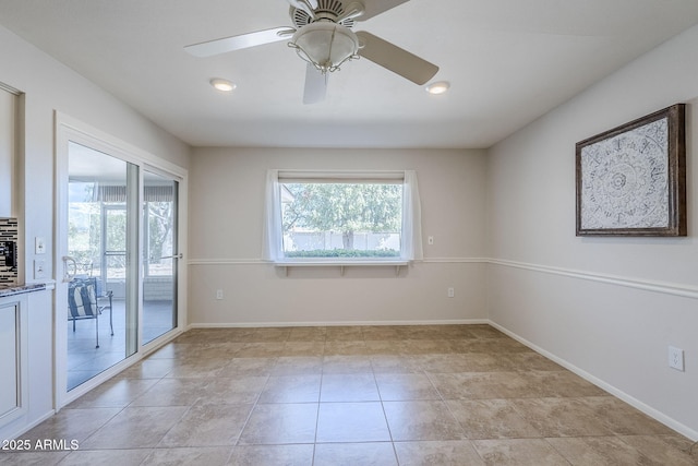 empty room featuring a healthy amount of sunlight, light tile patterned floors, and baseboards