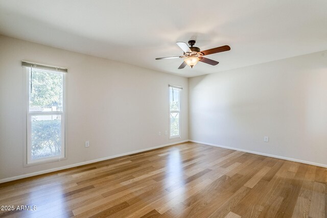 spare room with a wealth of natural light, baseboards, and light wood finished floors