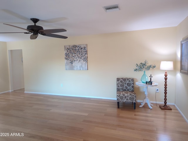 living area with baseboards, visible vents, ceiling fan, and light wood finished floors