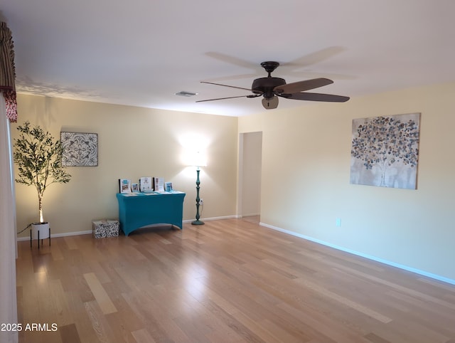 unfurnished room featuring a ceiling fan, visible vents, baseboards, and wood finished floors