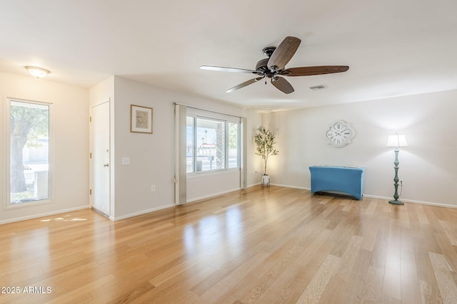 interior space featuring a ceiling fan, light wood-type flooring, visible vents, and baseboards