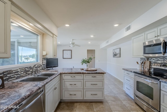 kitchen featuring stainless steel appliances, tasteful backsplash, visible vents, a sink, and a peninsula