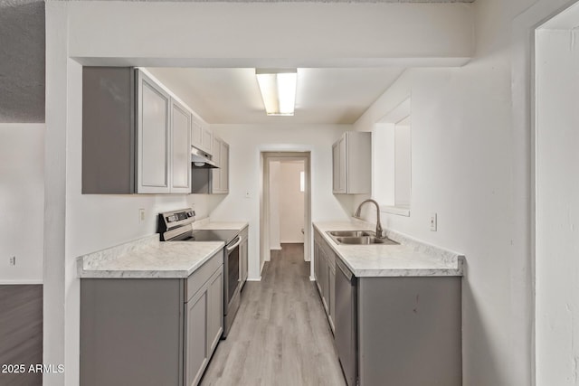 kitchen featuring light countertops, gray cabinets, stainless steel appliances, under cabinet range hood, and a sink