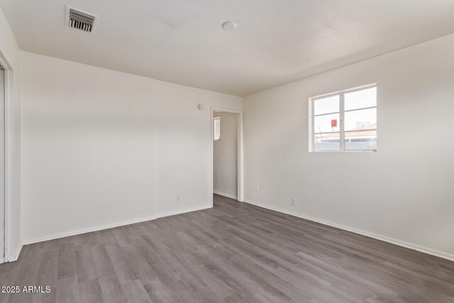 unfurnished room with baseboards, visible vents, and dark wood finished floors