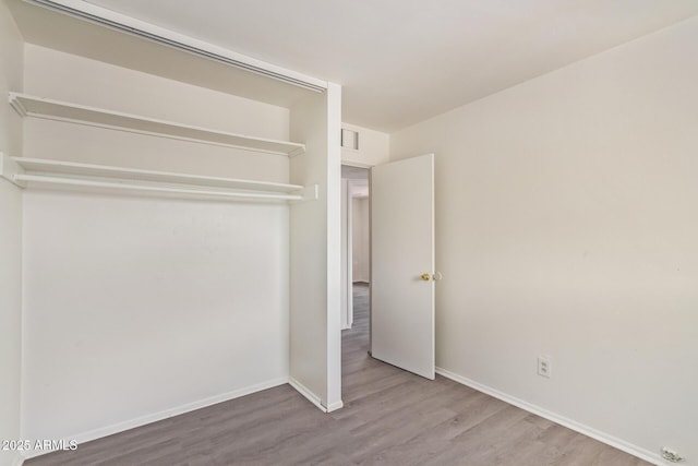 unfurnished bedroom featuring baseboards, visible vents, and wood finished floors