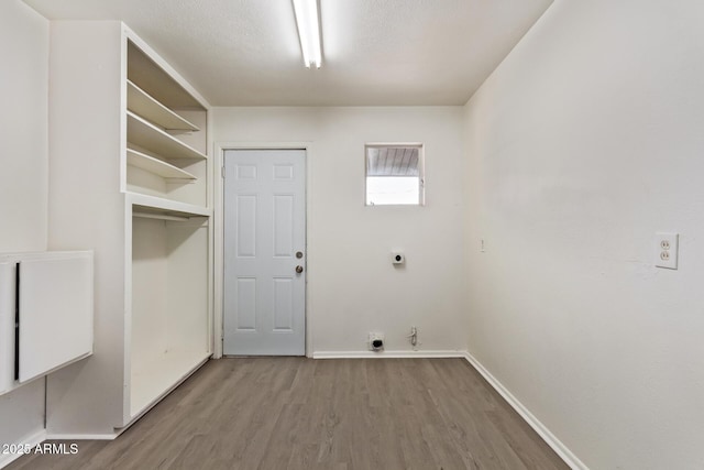 laundry area featuring hookup for a gas dryer, baseboards, wood finished floors, laundry area, and electric dryer hookup