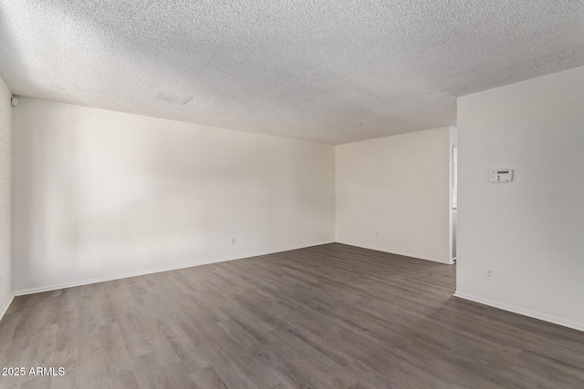 unfurnished room featuring dark wood-style flooring and a textured ceiling