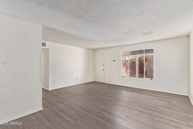 unfurnished room with visible vents, a textured ceiling, baseboards, and wood finished floors