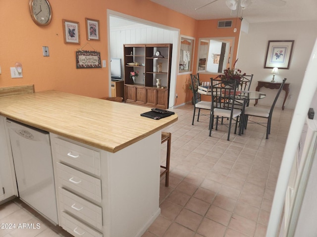 kitchen featuring dishwasher, kitchen peninsula, ceiling fan, white cabinetry, and a breakfast bar area