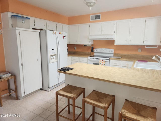 kitchen with kitchen peninsula, white appliances, sink, white cabinets, and a breakfast bar area