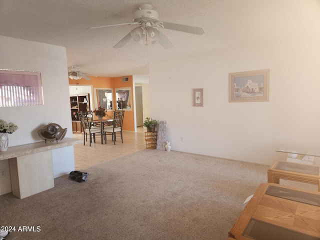 living room featuring ceiling fan, plenty of natural light, light colored carpet, and a textured ceiling