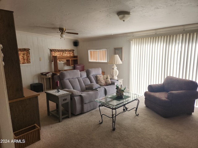 carpeted living room with ceiling fan, a textured ceiling, and wooden walls