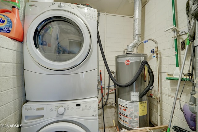 laundry area featuring water heater, stacked washer / dryer, and laundry area