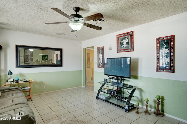 living area featuring light tile patterned floors, baseboards, a textured ceiling, and ceiling fan