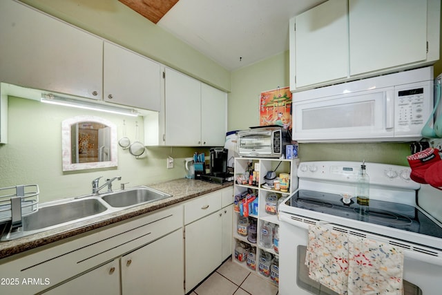 kitchen featuring light tile patterned floors, white cabinets, white appliances, and a sink