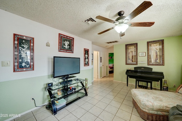 living room featuring a textured ceiling, light tile patterned flooring, visible vents, and ceiling fan