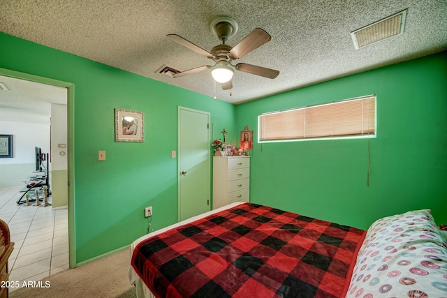 carpeted bedroom with tile patterned flooring, a ceiling fan, visible vents, and a textured ceiling