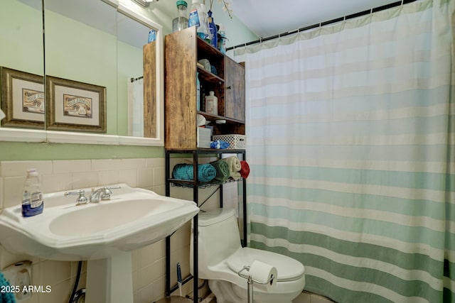 bathroom with a sink, decorative backsplash, curtained shower, tile walls, and toilet