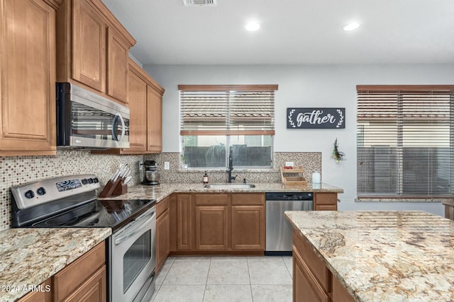 kitchen featuring sink, decorative backsplash, light stone countertops, light tile patterned flooring, and stainless steel appliances