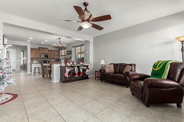 tiled living room featuring ceiling fan with notable chandelier