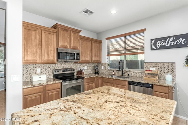 kitchen featuring light stone countertops, stainless steel appliances, tasteful backsplash, and sink