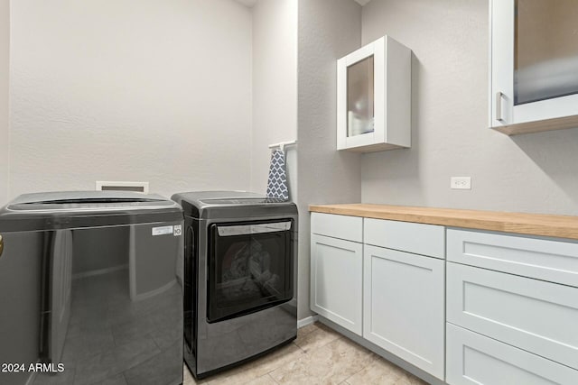 clothes washing area with washer and clothes dryer and cabinets