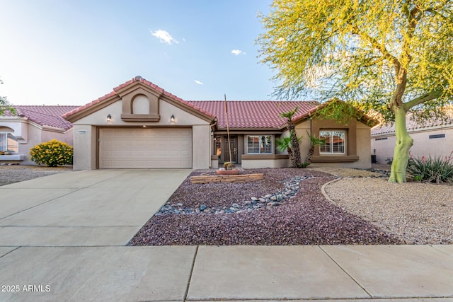 mediterranean / spanish-style home with a tiled roof, an attached garage, concrete driveway, and stucco siding